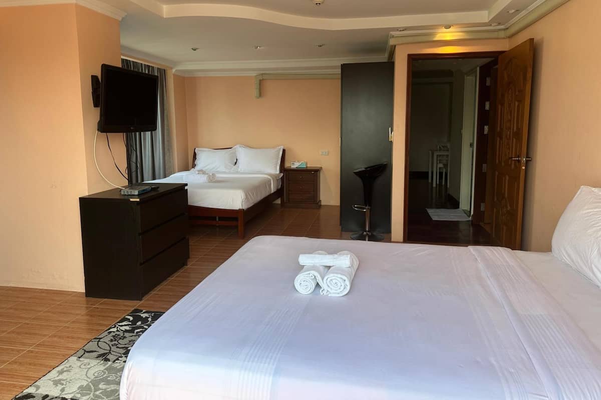 A hotel room with a large bed, a TV, a desk, and a chair.