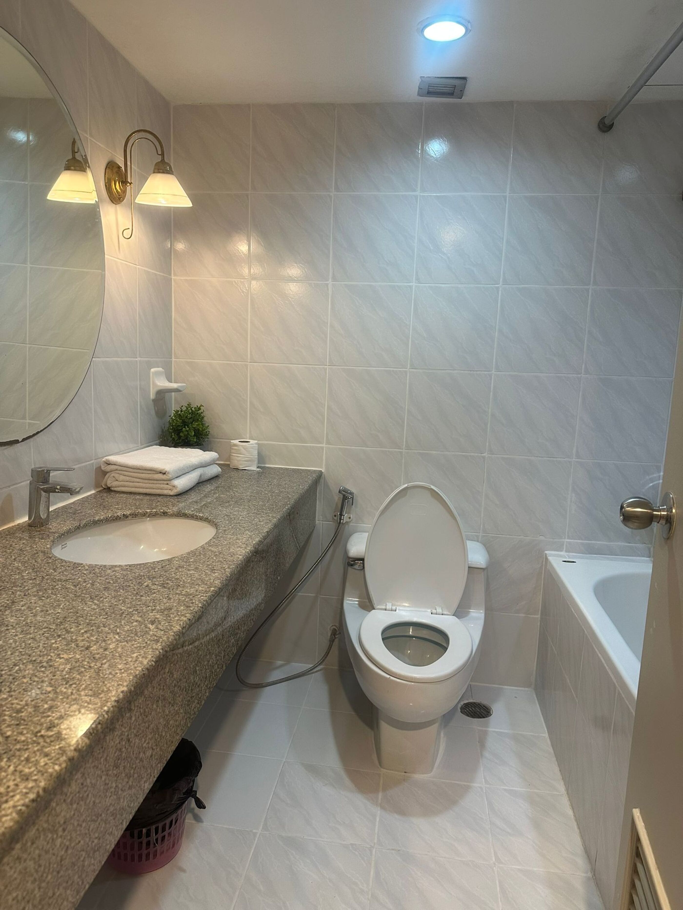A bathroom with a granite countertop, a toilet, and a bathtub.
