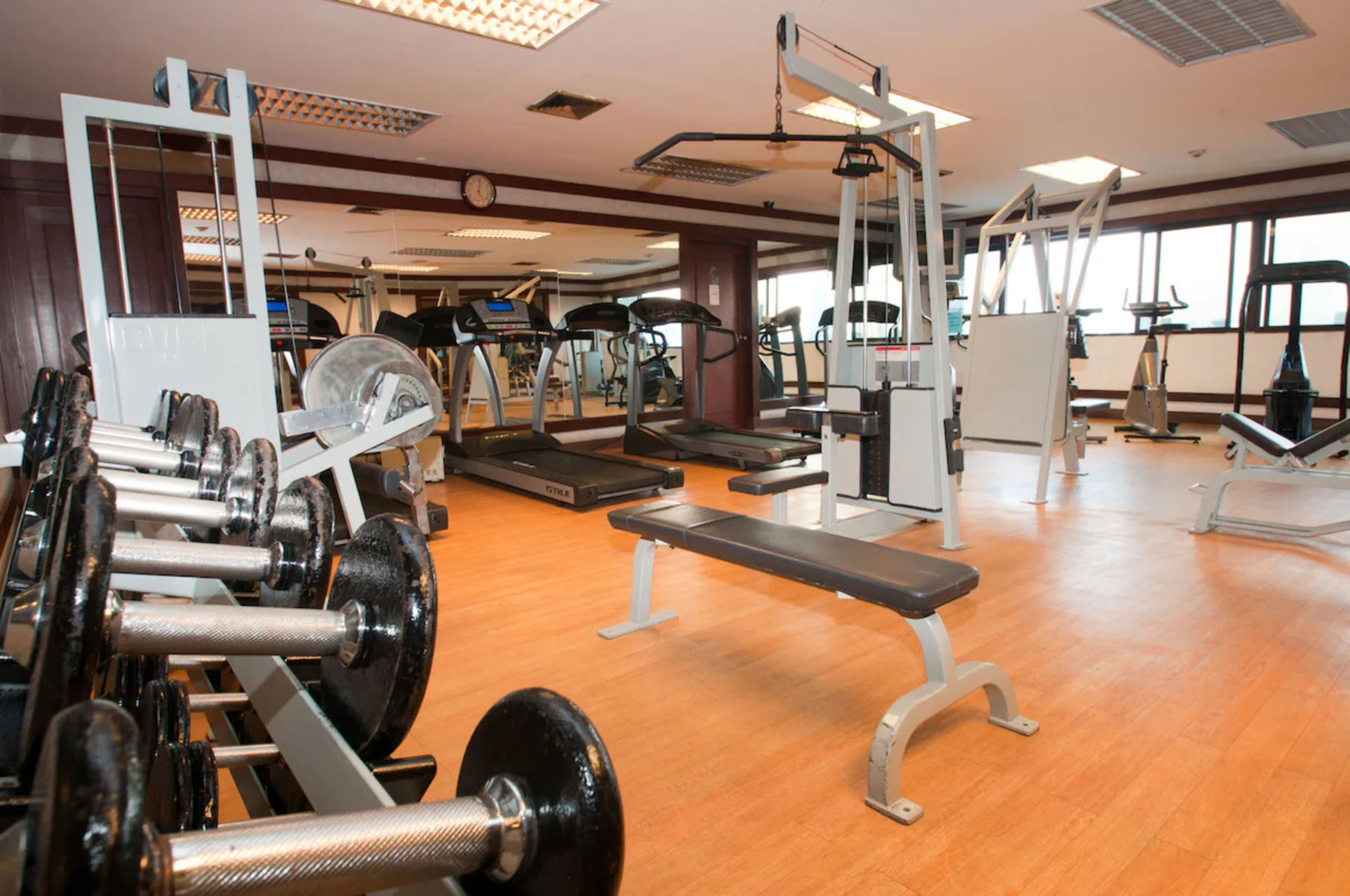 Une salle de sport équipée de divers appareils d’exercice, notamment des tapis de course, des appareils de musculation et des poids libres.