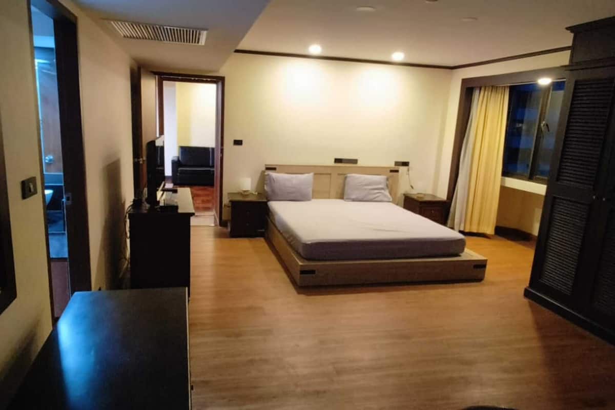 A hotel room with two beds, a desk, a wardrobe, and a television.