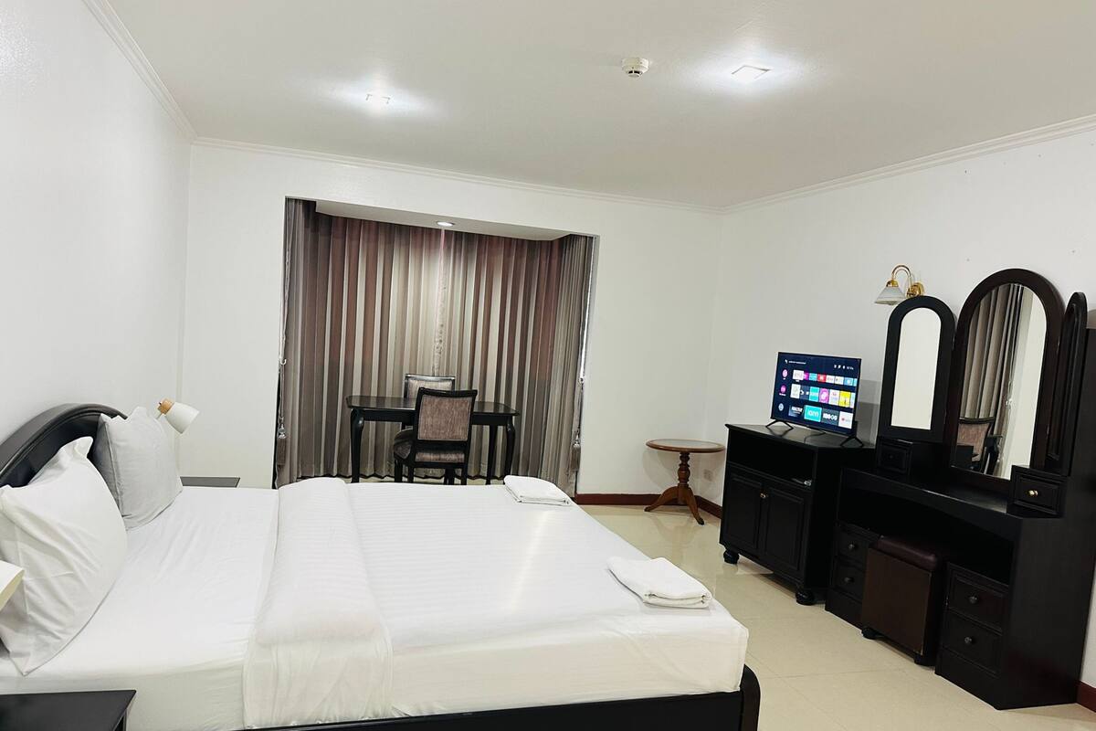 A hotel room with a bed, a desk, a television, and a mirror.