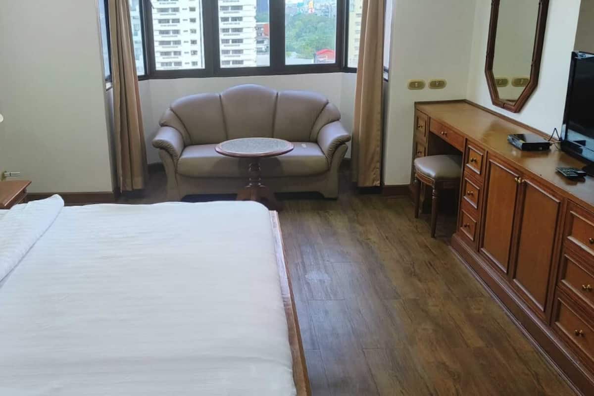 A hotel room with a bed, a desk, a chair, a television, and a window with curtains.