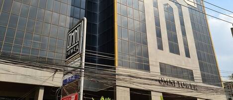 A modern building with a glass facade, a sign for 'OMNITOWER', and an ATM on the ground floor.