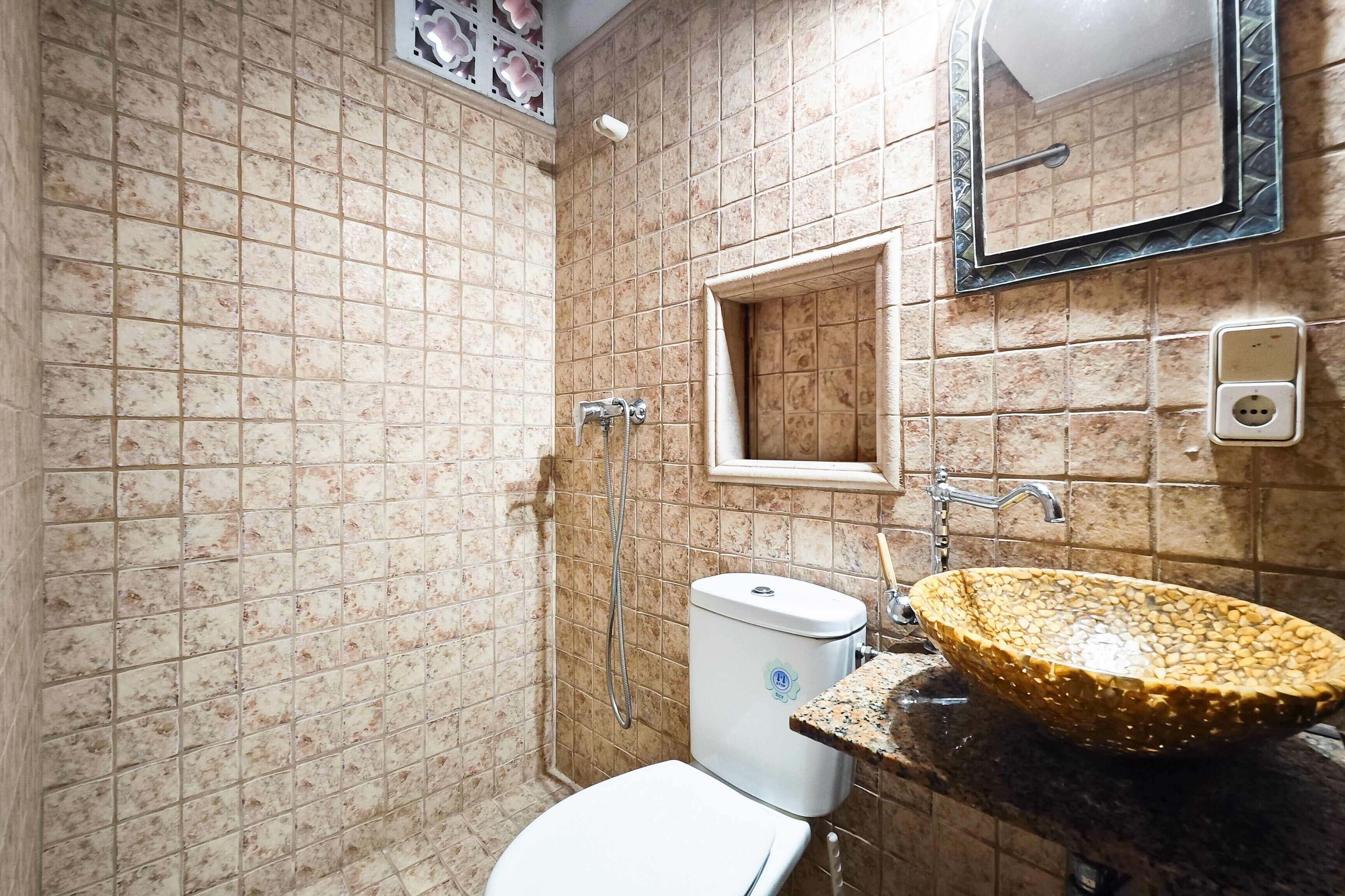 Un baño con inodoro, lavamanos, espejo, ducha y paredes de azulejos.