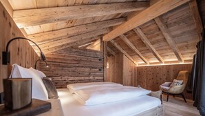 Een slaapkamer in een houten chalet met een bed, een stoel en een lamp.