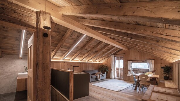 Een rustiek houten interieur met een slaaploft, een eethoek en een kitchenette.