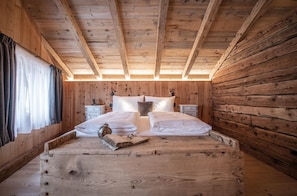 Une chambre à coucher dans une cabane en bois, avec un lit, des tables de chevet et une fenêtre avec des rideaux.