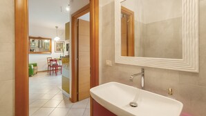 Ein Badezimmer mit Waschbecken, Spiegel und beigen Fliesen.