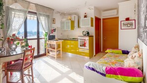 Ein Zimmer mit einem Bett, einem Schreibtisch, einem Stuhl, einer Küchenzeile und einem Esstisch.