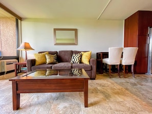 A living room with a brown sofa, two armchairs, a coffee table, and a mirror on the wall.