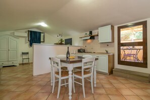 Une cuisine dotée d’un îlot central, de meubles blancs et d’un coin repas avec des chaises.