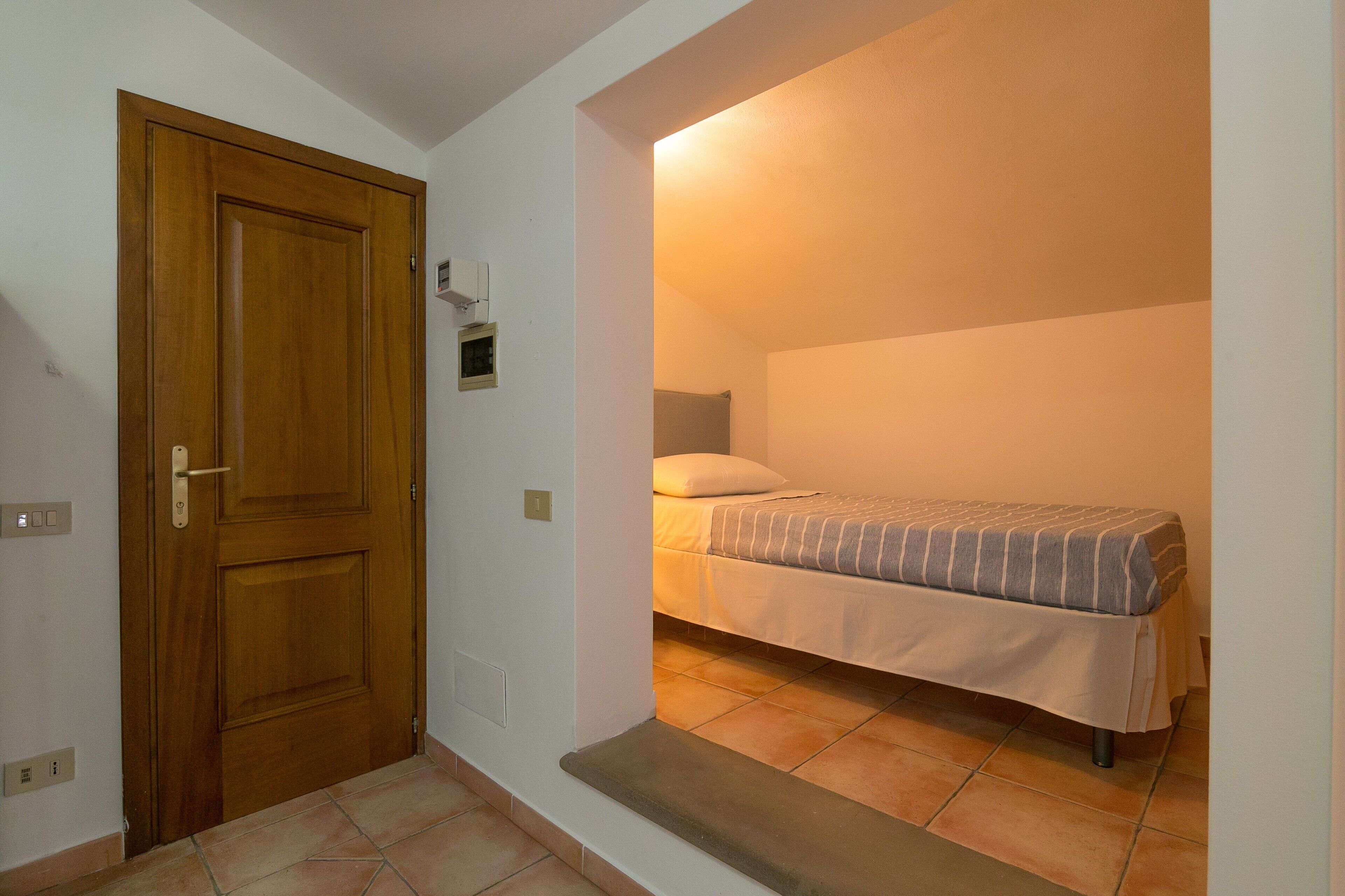 A bedroom with a bed, a wooden door, and a small window.