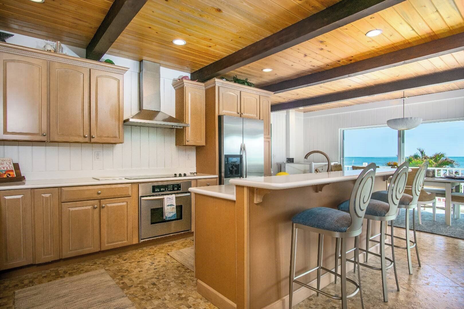 A kitchen with wooden cabinets, a stainless steel oven, and a bar area with stools.