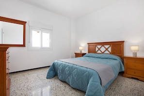 Una camera da letto con un letto, due comodini, una testiera in legno, uno specchio e una finestra.