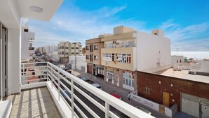 Un balcón con vistas a una calle, edificios y cielo despejado.