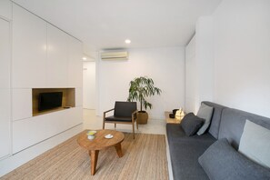 A modern living room with a sofa, a chair, a small table, a television, and a plant. - Holiday Apartment 'La Alameda' with Sea View, Wi-Fi, and Air Conditioning (Santa Cruz de Tenerife)