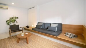 Una sala de estar moderna con un sofá, una butaca, una mesita y una planta.