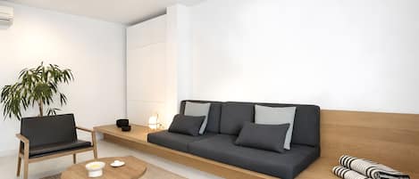 En moderne stue med sofa, stol, lille bord og en plante.