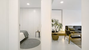 Una habitación moderna con una cama, una mesita, una silla, un sofá y una planta en maceta.