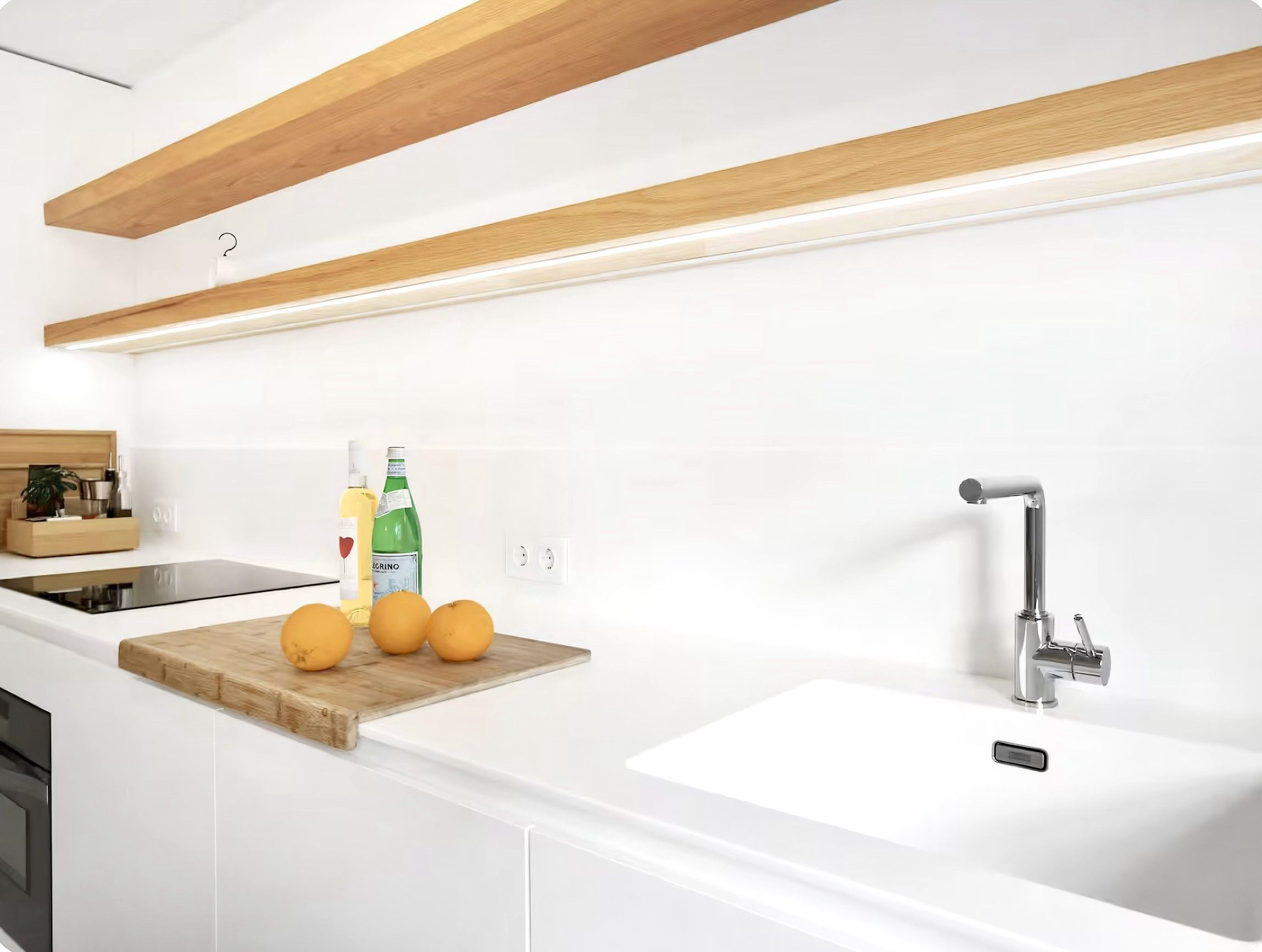 Een moderne keuken met witte kasten, een houten aanrecht, een spoelbak en een kraan.