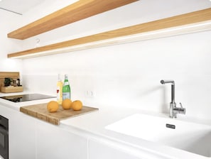 A modern kitchen with white cabinetry, a wooden countertop, a sink, and a faucet.