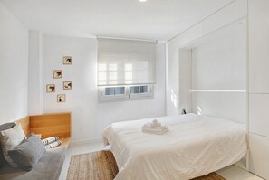 A bedroom with a bed, a wooden headboard, a window, and a wall-mounted TV. - Holiday Apartment 'La Alameda' with Sea View, Wi-Fi, and Air Conditioning (Santa Cruz de Tenerife)