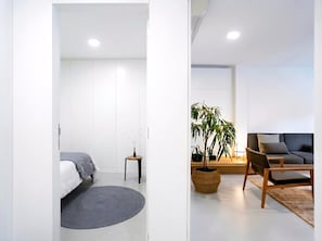 Un dormitorio moderno con cama, mesita de noche y una planta en maceta.