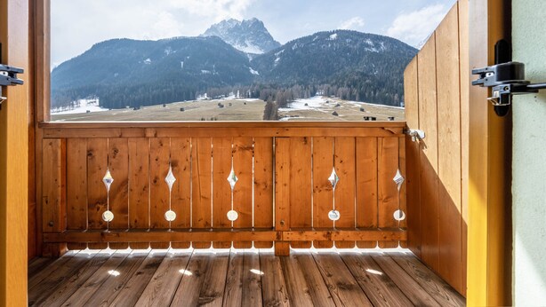 Een houten balkon met uitzicht op besneeuwde bergen en een heldere lucht.