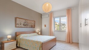 Ein Schlafzimmer mit Bett, Nachttisch, Lampe und einem Gemälde an der Wand.