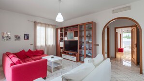 Ein Wohnzimmer mit einem roten Sofa, einem weißen Sofa und einer TV-Konsole.