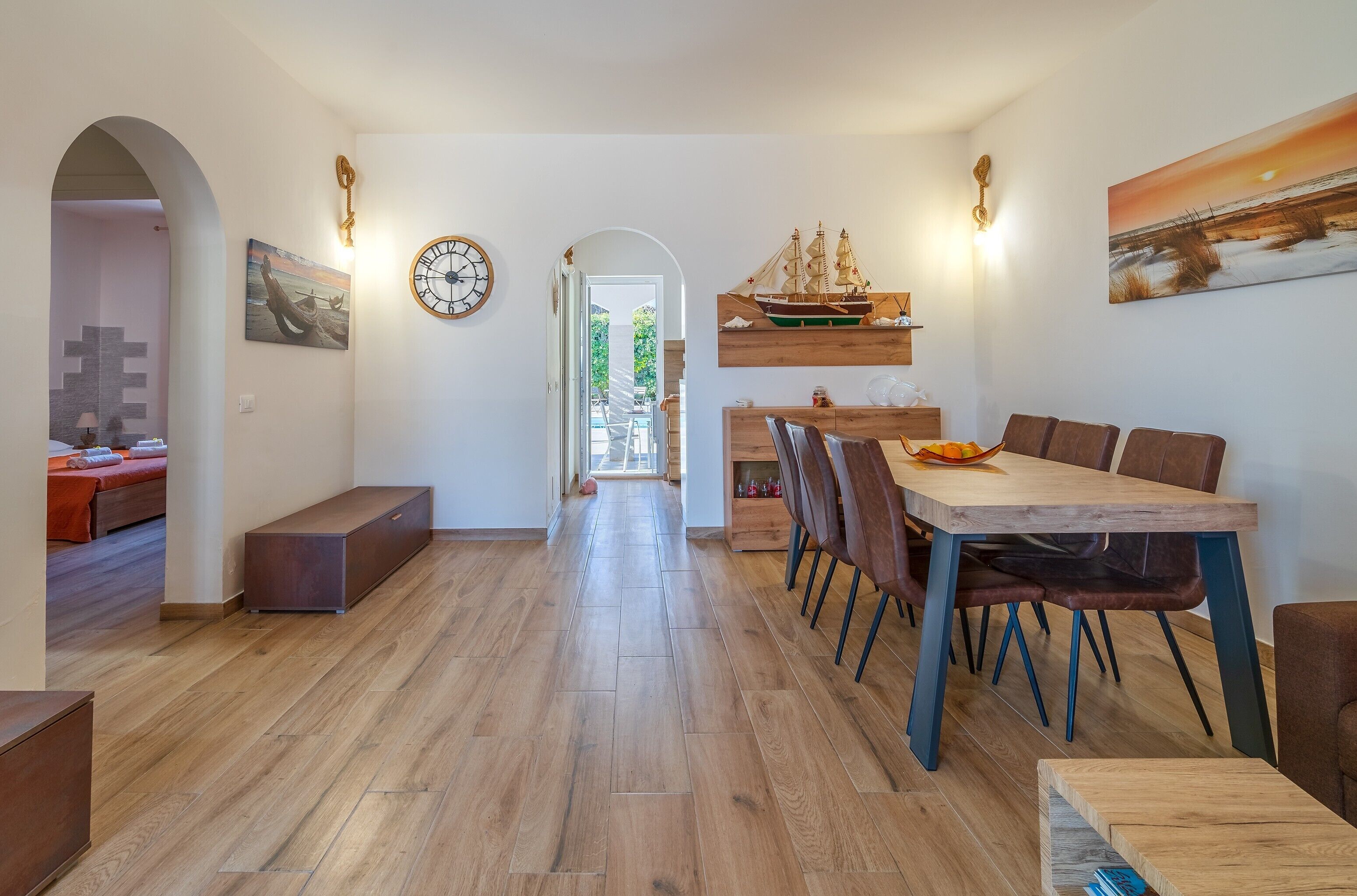 A dining area with a wooden table and chairs, a bench, and a ship model on the wall.
