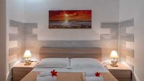 A hotel room with a bed, two bedside tables, a wall-mounted painting, and a nightstand with a lamp. - Villa 'Villa Gioia Fontane Bianche' with Sea View, Wi-Fi and Air Conditioning (Siracusa)