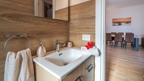 A modern bathroom with a sink, mirror, and wooden wall paneling. - Villa 'Villa Gioia Fontane Bianche' with Sea View, Wi-Fi and Air Conditioning (Siracusa)