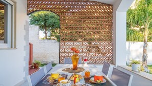 An outdoor dining area with a table set for breakfast, including pastries, a fruit bowl, and beverages. - Villa 'Villa Gioia Fontane Bianche' with Sea View, Wi-Fi and Air Conditioning (Siracusa)