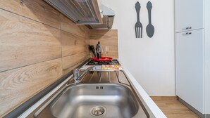 A modern kitchen with a stainless steel sink, wooden cabinetry, a gas stove, and a white refrigerator. - Villa 'Villa Gioia Fontane Bianche' with Sea View, Wi-Fi and Air Conditioning (Siracusa)