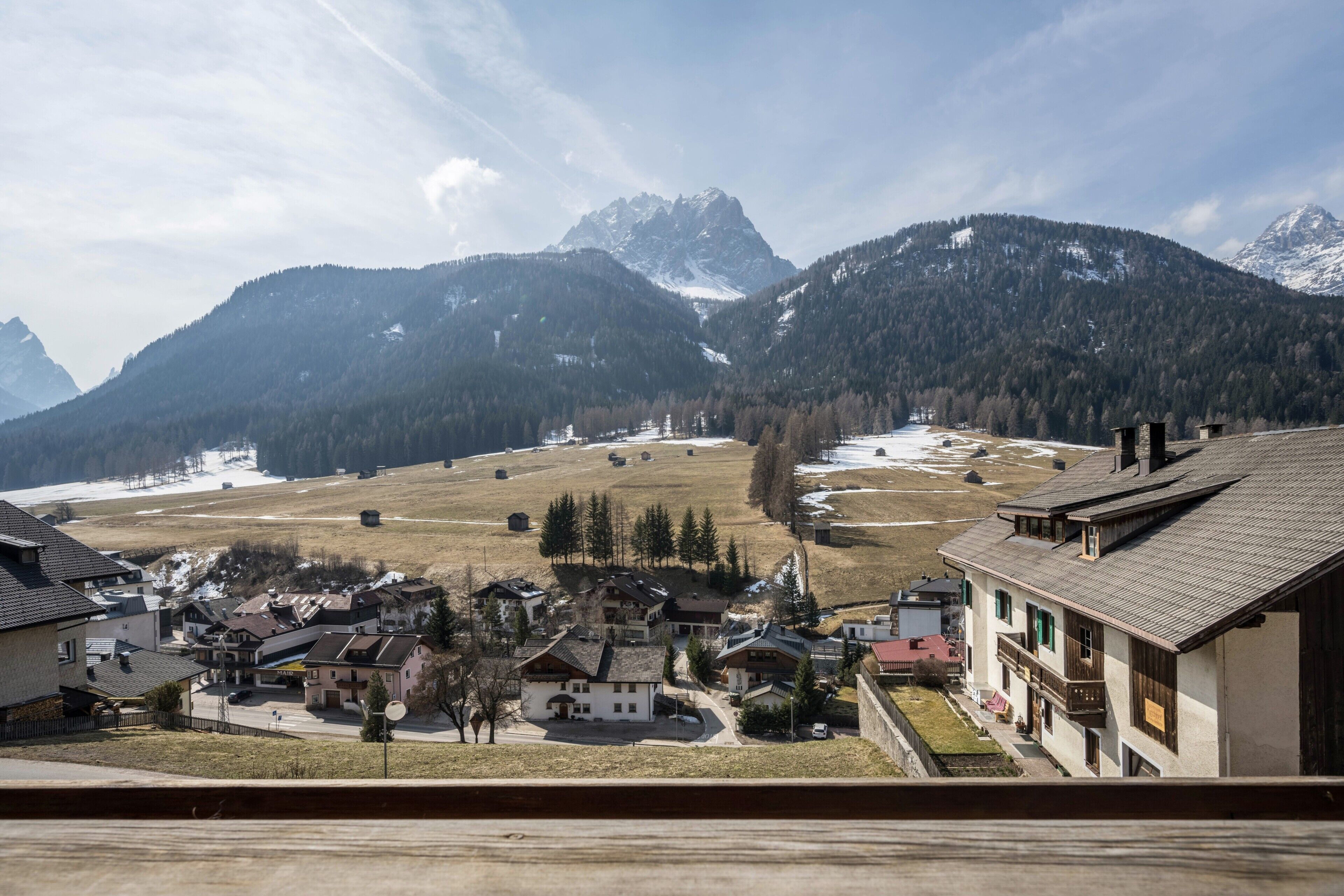 Un village de montagne à l’architecture traditionnelle, offrant une vue dégagée sur les montagnes environnantes et un paysage enneigé.