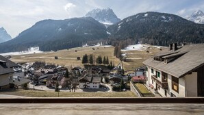 Un borgo montano dall'architettura tradizionale, con vista libera sulle montagne circostanti e un paesaggio innevato.