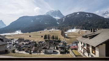 Ein Bergdorf mit traditioneller Architektur, freiem Blick auf die umliegenden Berge und einer verschneiten Landschaft.