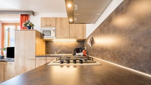 Una cucina moderna con mobili in legno, piano cottura a gas, forno a microonde e forno integrato.