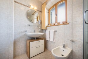A modern bathroom with a sink, vanity, mirror, and window.