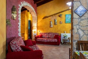 A cozy interior with a red sofa, a stone wall, and a decorative archway.