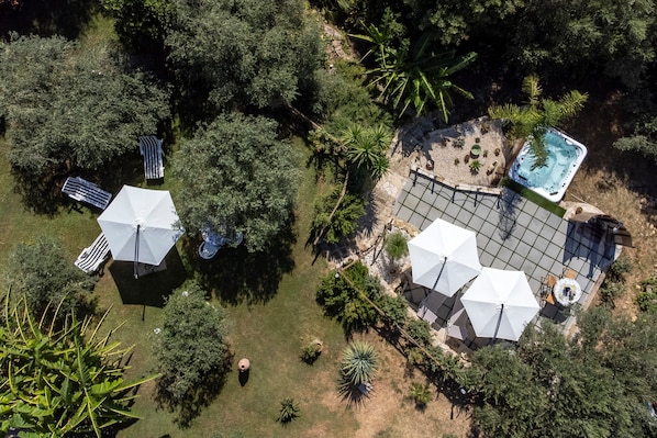 An aerial view of a garden with a swimming pool, umbrellas, and seating areas.