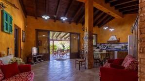A spacious living area with a red sofa, a television, and a dining area with chairs and a table. - Villa 'Il Melograno' with Private Terrace,  Jacuzzi, Wi-Fi and Air Conditioning (Menfi)