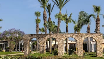 Une arche en pierre, avec des palmiers en arrière-plan.