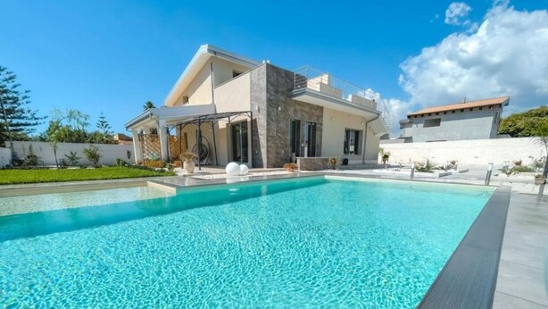 Une maison moderne dotée d’une piscine, d’un patio couvert et d’une façade blanche.