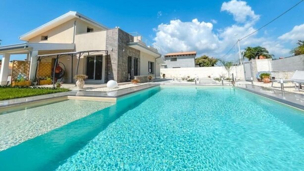 A modern house with a swimming pool, a covered patio, and a clear blue sky. - 'Nord in Villa Sele' Apartment with Shared Pool, Wi-Fi, and Air Conditioning (Fontane Bianche)