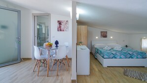 A modern bedroom with a bed, bedside table, and a small sitting area with a table and chairs. - 'Nord in Villa Sele' Apartment with Shared Pool, Wi-Fi, and Air Conditioning (Fontane Bianche)
