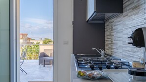 A modern kitchen with a gas stove, a sink, and a view of the outside patio. - Apartment 'Sud In Villa Sele' with Sea View, Wi-Fi and Air Conditioning (Fontane Bianche)