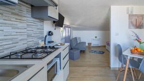 A modern kitchen with a gas stove, oven, and a dining area with a table and chairs. - Apartment 'Sud In Villa Sele' with Sea View, Wi-Fi and Air Conditioning (Fontane Bianche)