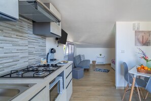 A modern kitchen with a gas stove, oven, and a dining area with a table and chairs.